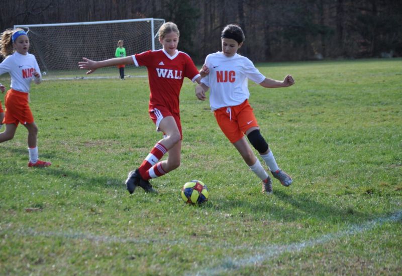 The girls playing soccer in ground